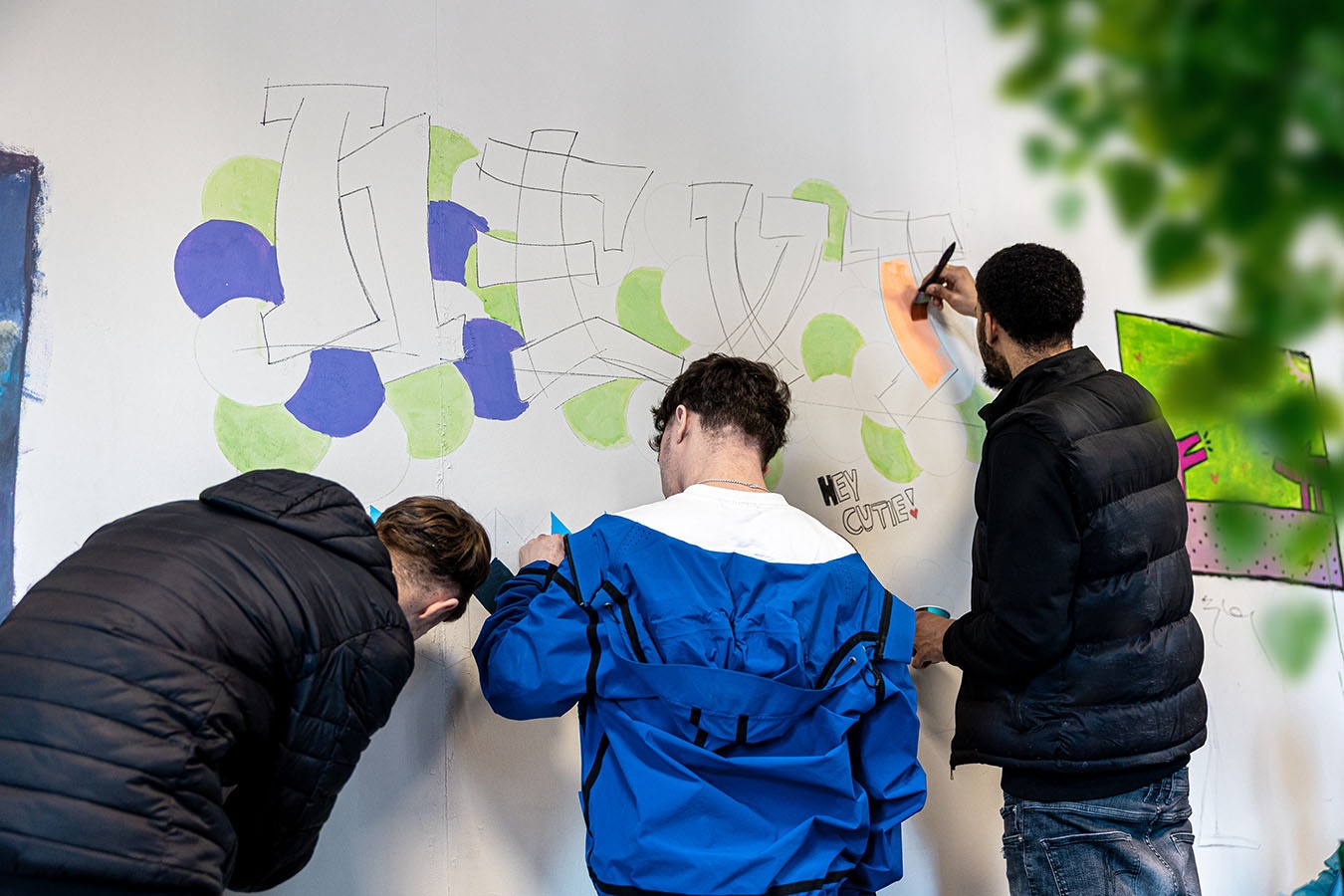 Drie mbo-jongeren verven een muur bij Talenthub