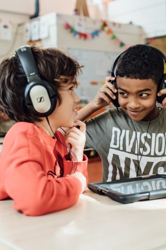 Twee kinderen met koptelefoon in een klaslokaal