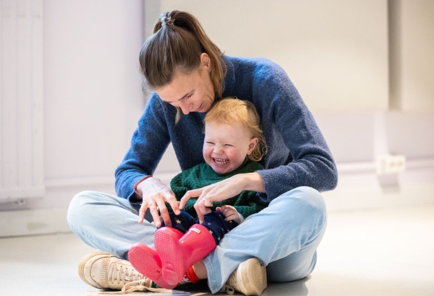 Volwassen vrouw met jong lachend kind zittend op de grond
