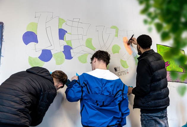 Jongeren die werken aan een mural